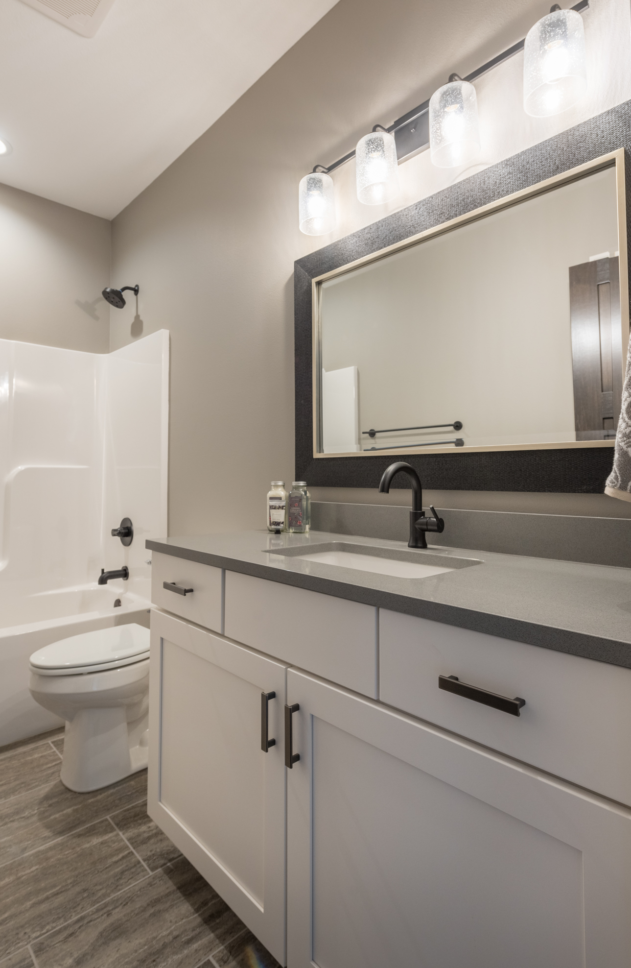Cabinet Installation - Bathroom with white cabinetry, dark hardware, gray countertop and modern lighting fixtures